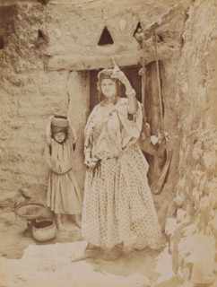 Unknown woman with spinning wheel, behind her a child, photograph, inscription: 'illegible',