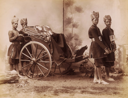 Studio portrait of four Indian men in uniform with a carriage, India, photograph, inscription: