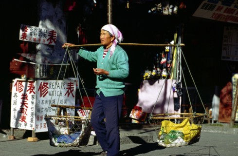 Femme transportant des paniers de fruits sur les épaules