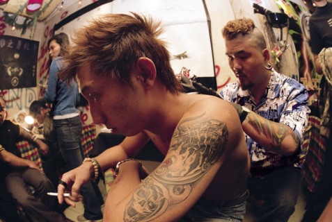 A man marks a tatto on a man's back