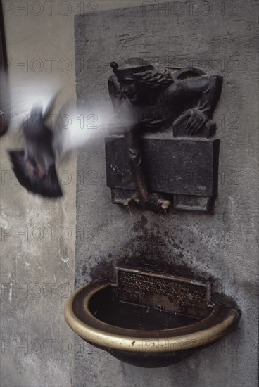 FUENTE ADOSADA A UNA PARED CON UNA PALOMA VOLANDO
INNSBRUCK, EXTERIOR
AUSTRIA

This image is