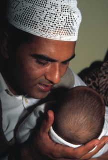 Un père musulman chuchote le "shahada" à l'oreille de son nouveau-né
