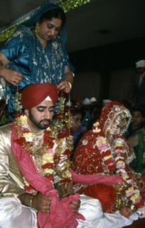 A mother garlands the groom for his wedding, India