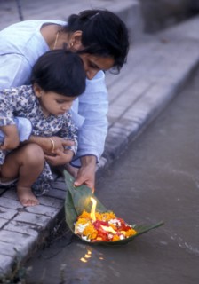 Child setting a lighted boat on the Ganges at Divali in India