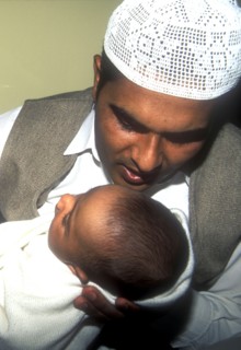 Father whispers opening words of the Muslim prayer in his newborn baby`s ear