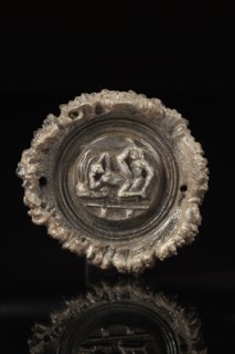 Phalère circulaire sculptée au centre d'une scène érotique