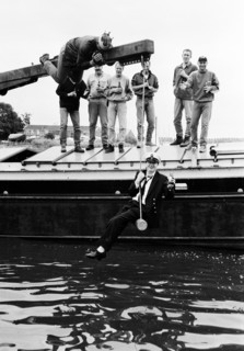 Groupe d'hommes debout sur un ponton au bord de l'eau, lors d'un enterrement de vie de garçon.