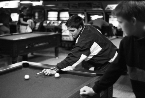 Two young people playing pool in a games arcade, with arcade machines in the background. Castlebar,