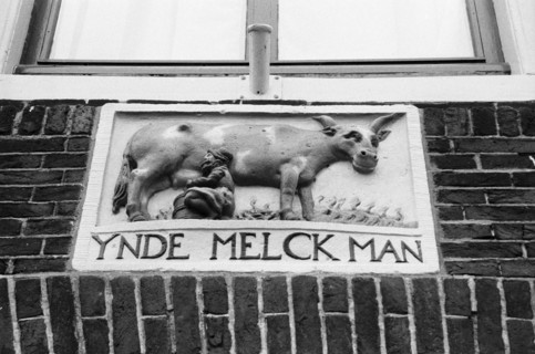 Pierre de façade sculptée en relief, portant l'inscription « Ynde Melck Man », sur un mur de