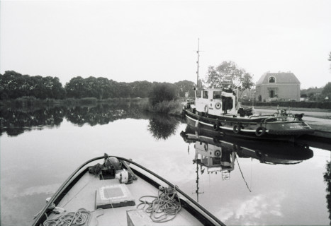 L'Amstel vue depuis la proue d'un bateau, un bateau amarré plus loin et des arbres sur la berge.