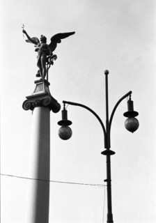 Figure ailée au sommet d'une colonne et lampadaire à deux globes, vus en contre-plongée. Prague,