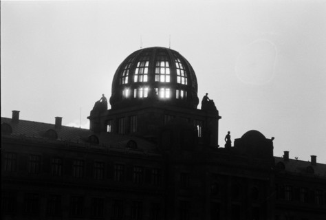 Silhouette sombre d'un bâtiment surmonté d'un dôme dont les fenêtres sont éclairées. Prague,
