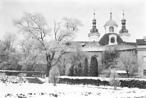 Édifice à deux tours et à coupole sous la neige, derrière des arbres nus. Prague, République