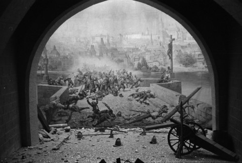 Diorama représentant une scène de bataille, avec un canon au premier plan, vu à travers une arcade.