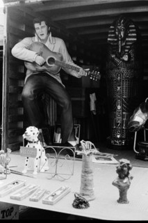 Marché aux puces : figurine grand format d'Elvis jouant de la guitare et divers objets à la vente.
