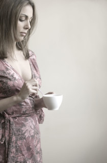 Profile of woman stirring coffee.
