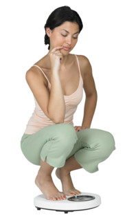 A woman weighing herself on a scale.