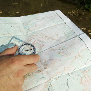 Hand holding a compass and map.