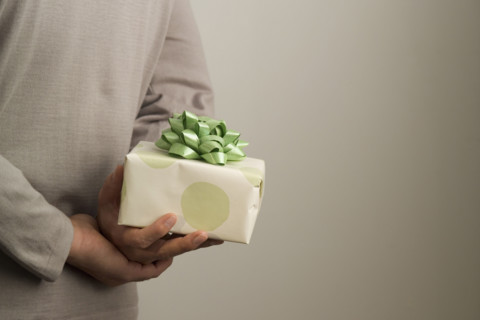 Man hiding a gift behind his back.
