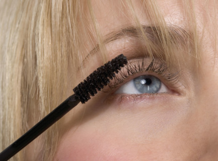 Woman's eye with mascara brush.