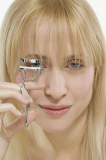 Woman using eyelash curler.