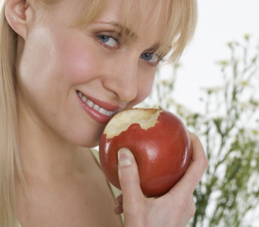 Smiling woman eating apple.