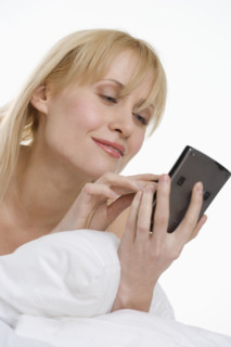 Woman using PDA in bed.