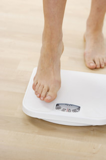 Feet stepping onto bathroom scale.
