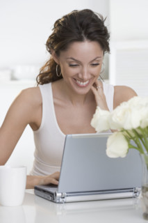 Smiling woman with laptop and cup.