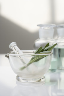 Glass mortar and pestle with herbs.
