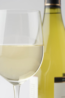 Glass of white wine with bottle.