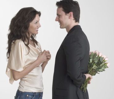 Man hiding bouquet from woman.