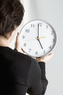Man from behind holding clock.