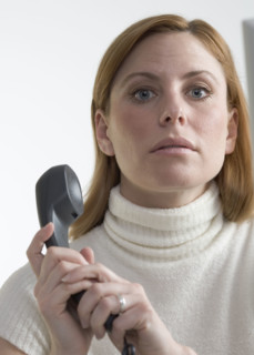 Woman covering mouthpiece of phone.