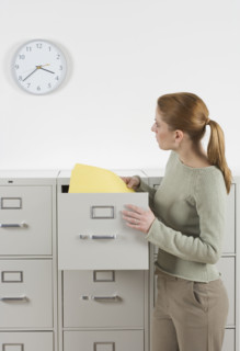 Woman with files looking at clock.