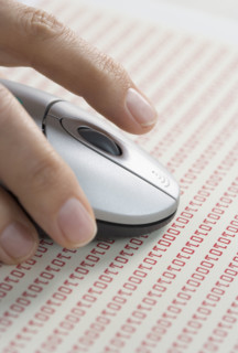 Hand on mouse with computer code.