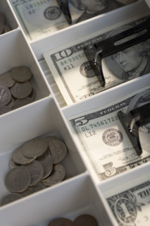 U.S. bills and coins in cash register.