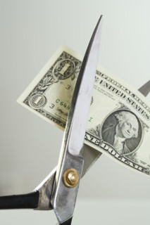 Closeup of scissors cutting money.