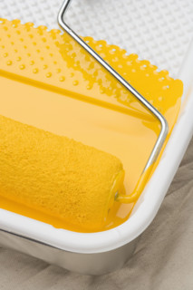 Still life of paint roller with yellow paint.