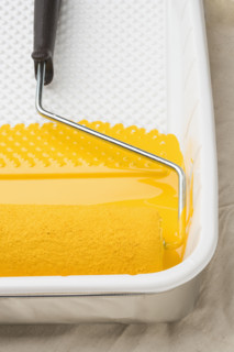 Still life of paint roller with yellow paint.