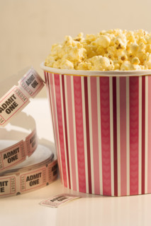 Still life of popcorn and ticket to a movie.