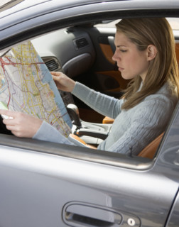 Woman in car looking at a map.