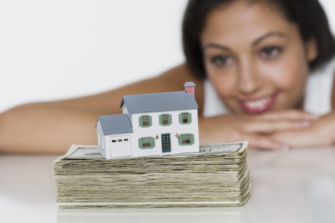 Woman with miniature house and money.