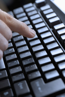 Closeup of finger and computer keyboard.
