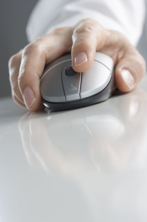 Hand on computer mouse with reflection.