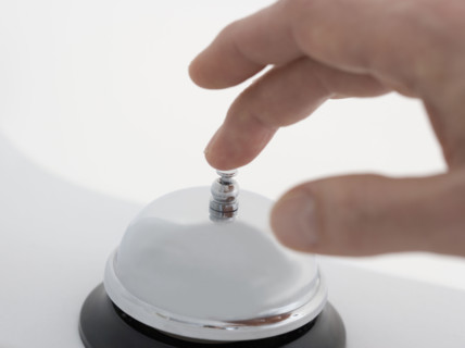 Closeup of hand ringing desk bell.