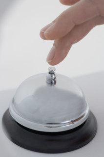 Closeup of finger ringing desk bell.