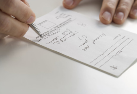 Closeup of hands signing prescription.