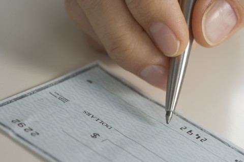 Closeup of hand writing check.
