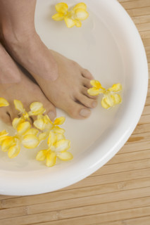 Feet in footbath with flowers.